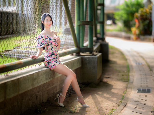 Улыбающаяся азиатка сидит у забора