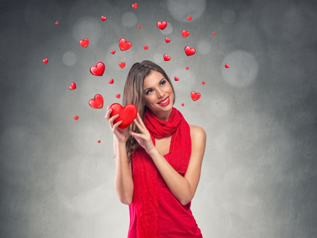Улыбающаяся девушка в красном платье с сердечками на сером фоне