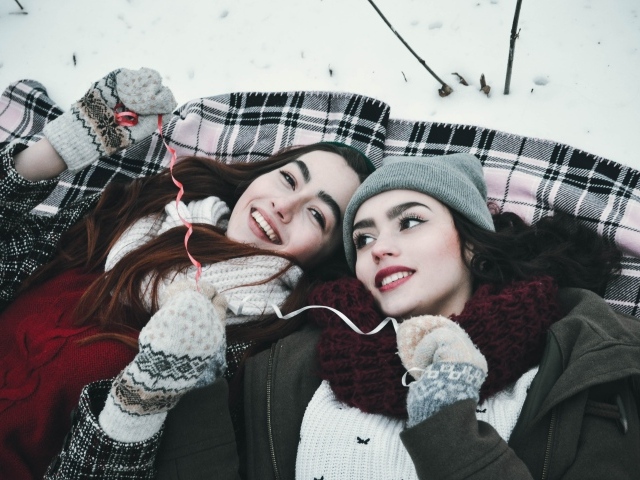 Две красивые молодые девушки лежат на снегу