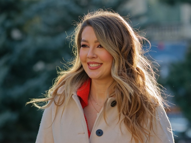 Женщина с милой улыбкой в пальто на улице