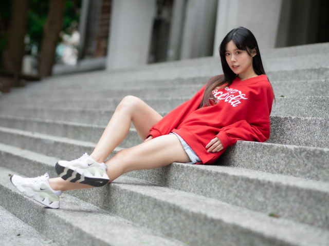 Молодая азиатка в кроссовках лежит на лестнице