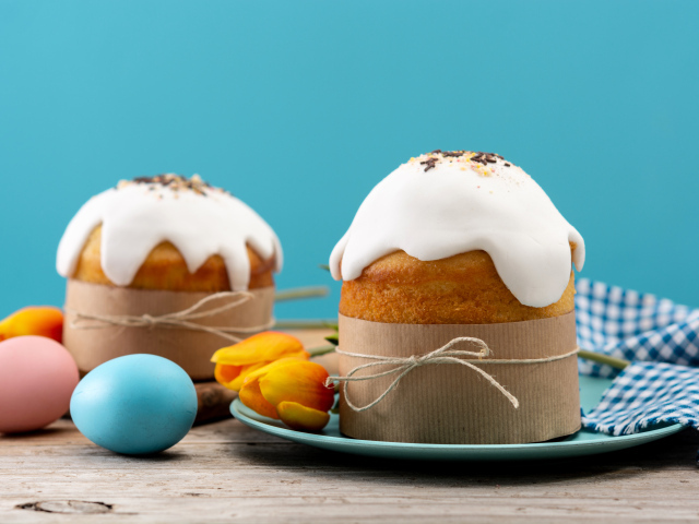 Пасхальные куличи с белой глазурью на столе с яйцами