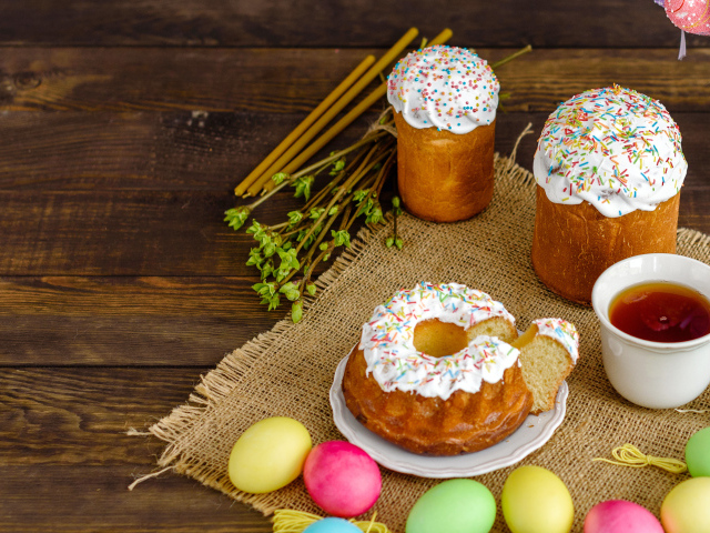 Сладкие пасхальные куличи на столе с чаем и крашеными яйцами