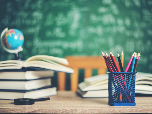 Карандаши на столе с книгами в школьном классе