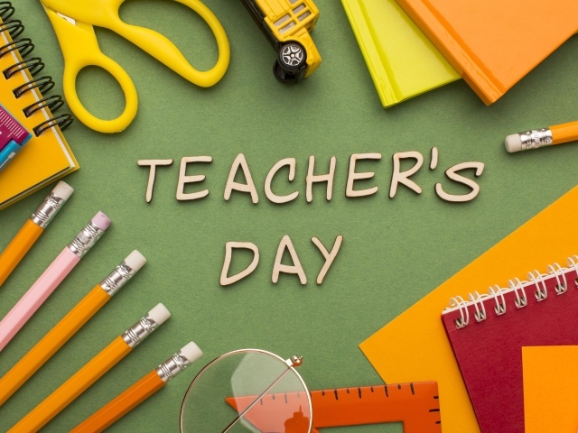 Канцелярские предметы на зеленом столе на день учителя