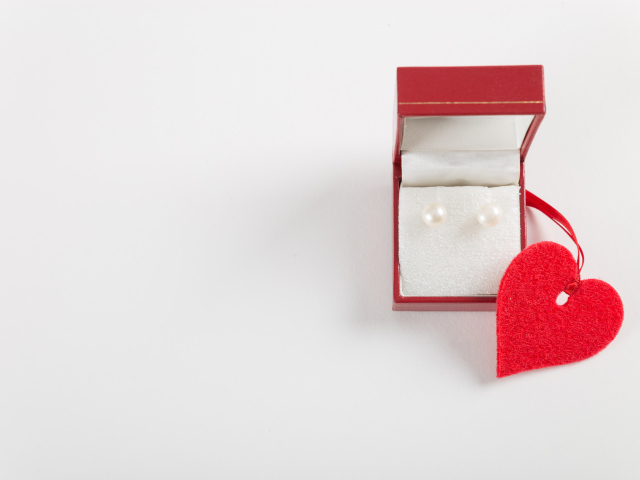 Красная коробка с жемчужными сережками с сердцем на красном фоне