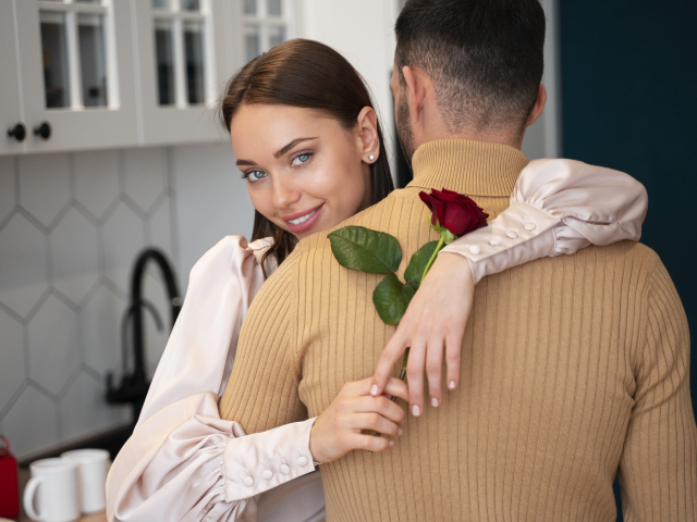 Влюбленная девушка с розой обнимает парня