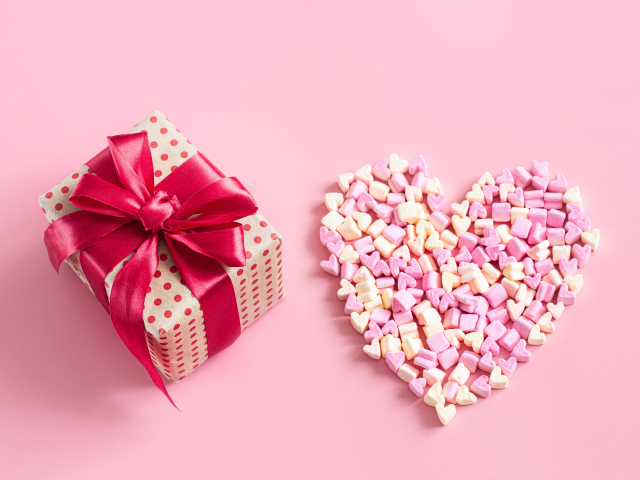 Подарок и сердце из конфет на розовом фоне