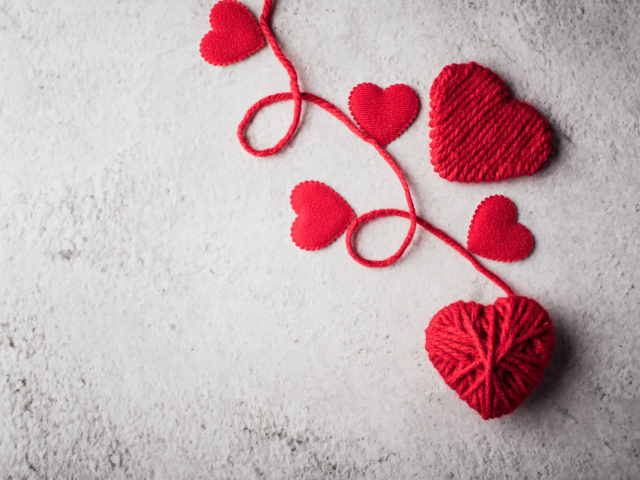 Сердечки из красной шерстяной нити на сером фоне