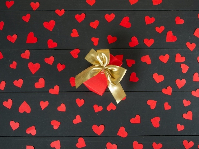 Много маленьких бумажных сердечек с подарком на столе
