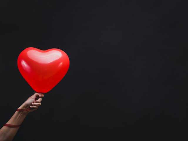 Красный шарик в форме сердца на черном фоне
