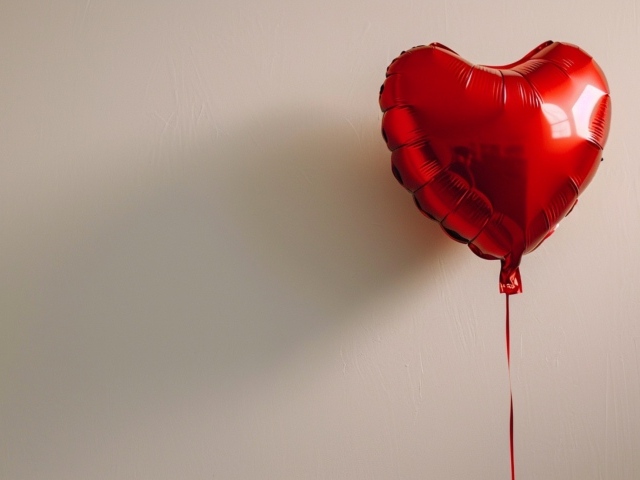 Красный шарик в форме сердца на сером фоне