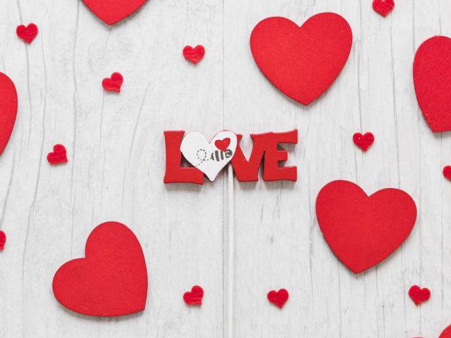 Надпись любовь с красным сердечками на деревянном фоне