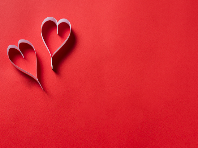 Два белых бумажных сердца на красном фоне
