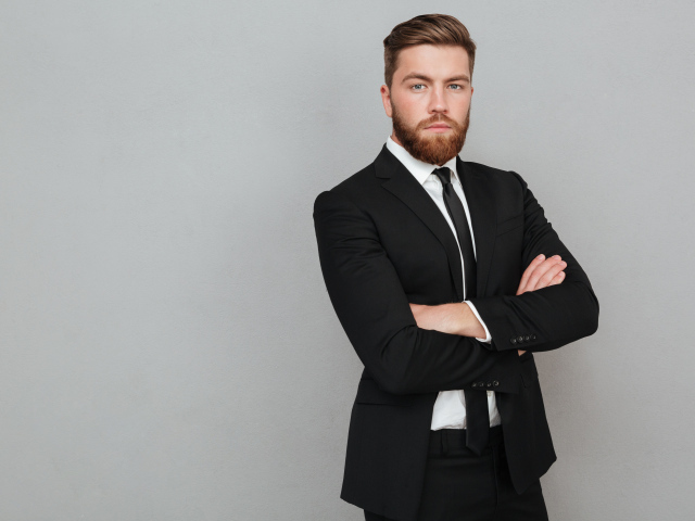 Деловой стильный мужчина в черном костюме на сером фоне