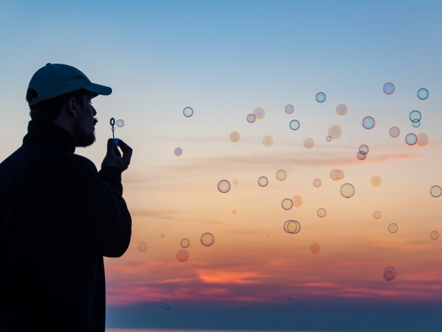 Мужчина пускает мыльные пузыри на закате