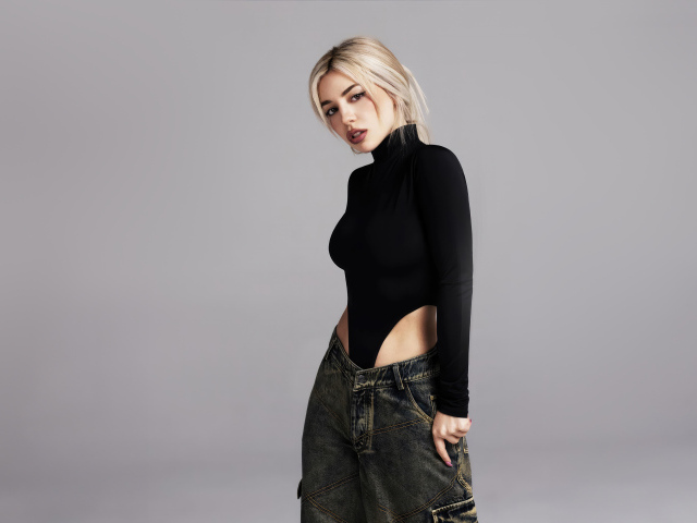 Милая блондинка певица  Эйва Макс на сером фоне