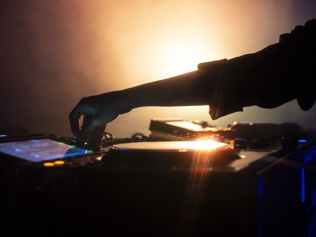 Рука диджея настраивает музыкальный пульт 