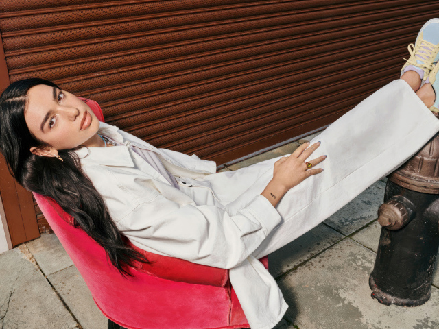 Певица Дуа Липа в белом костюме сидит в кресле