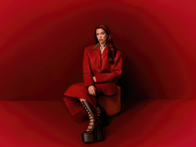 Певица Дуа Липа позирует на красном фоне