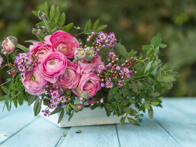 Букет розовых цветов лютика в ящике на голубом столе