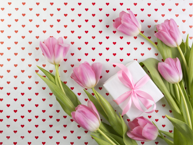 Букет розовых тюльпанов и подарок на фоне с сердечками
