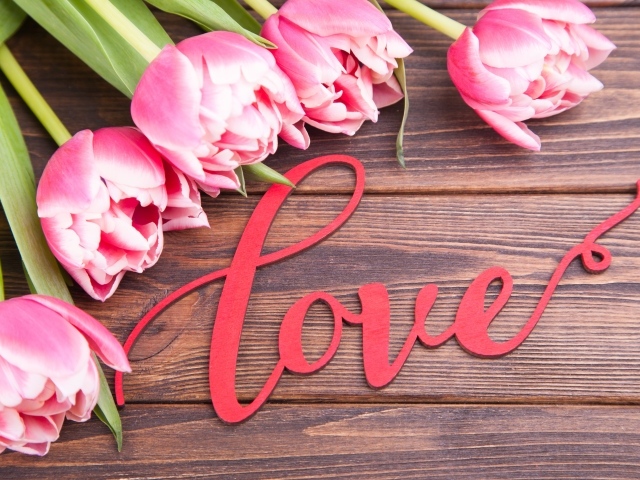 Букет розовых тюльпанов с надписью любовь на деревянном столе