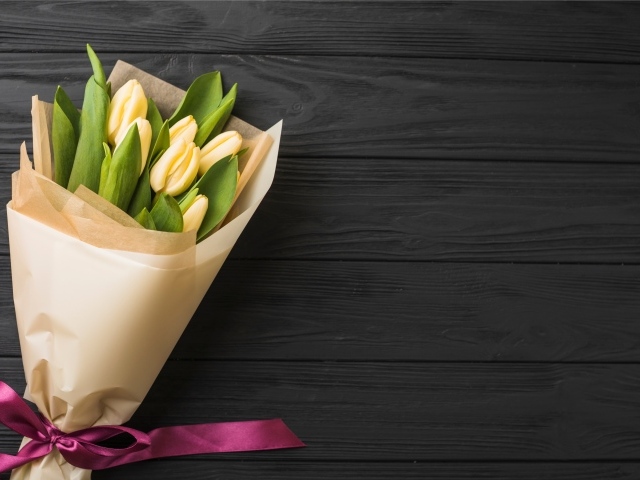 Букет желтых тюльпанов в бумажной упаковке с лентой