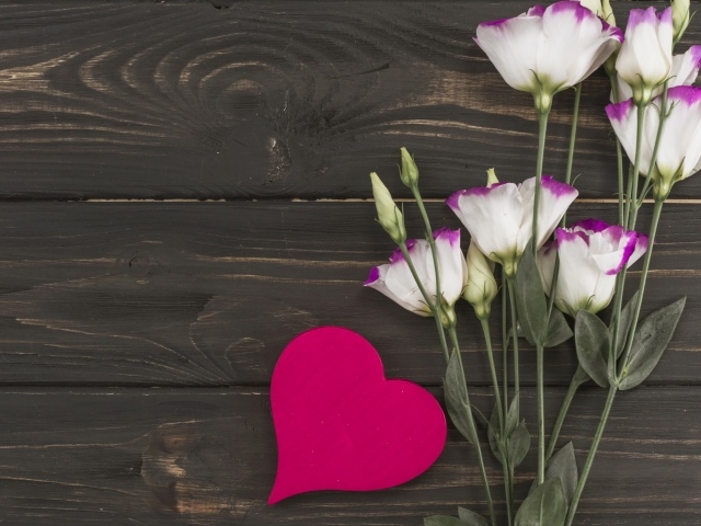 Нежные цветы эустомы с красным сердцем на деревянном фоне