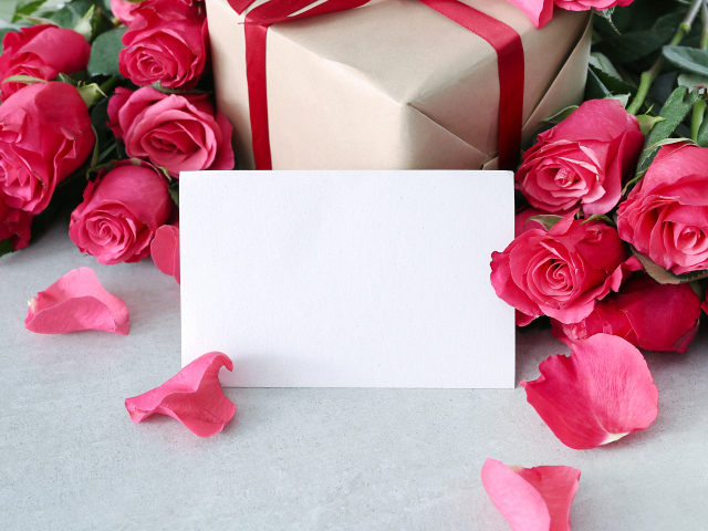 Лист бумаги с розовыми розами и подарком для открытки
