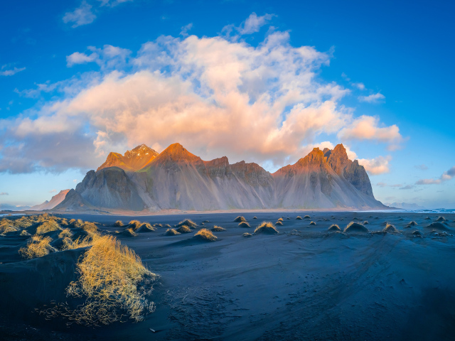 Облако в голубом небе над покрытой солнцем горой