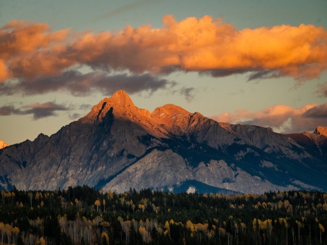Солнце в облаках освещает вершину горы