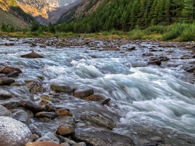 Быстрая холодная река стекает по камням в горах 