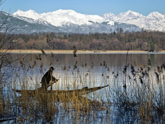 Рыбак плывет по воде на фоне заснеженных гор