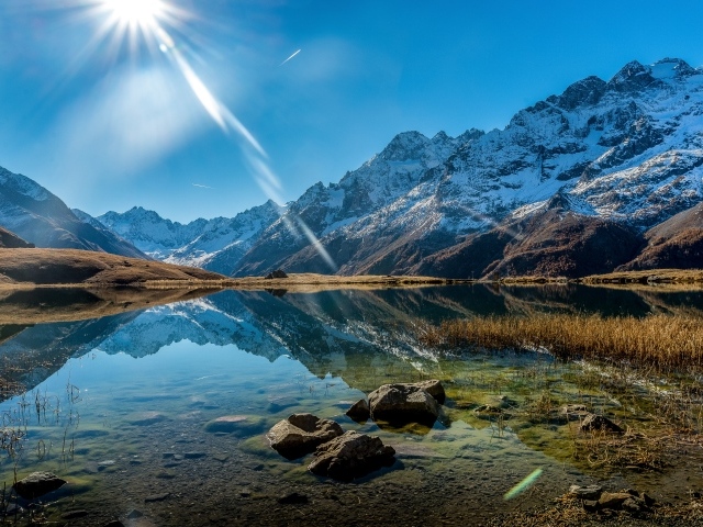 Лучи яркого солнца освещают гору и озеро