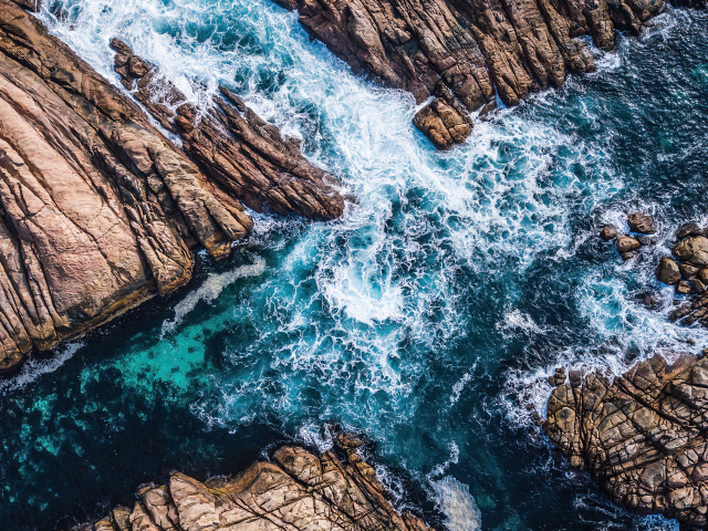 Вид на бушующее голубое море между камней 