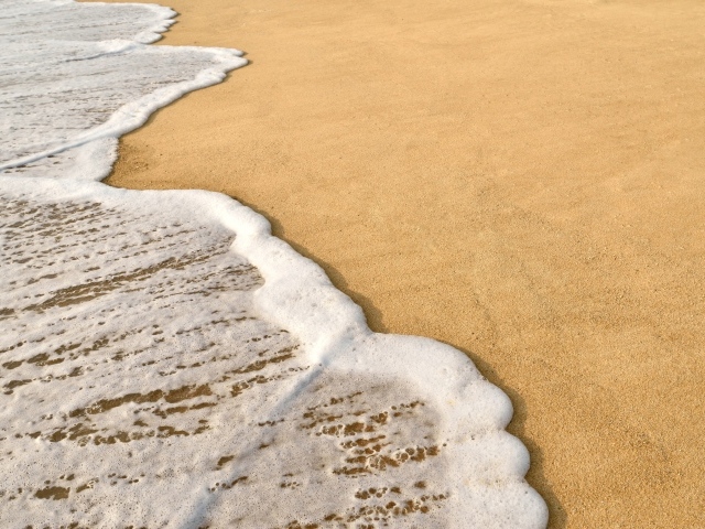 Белая пена на горячем песке на пляже