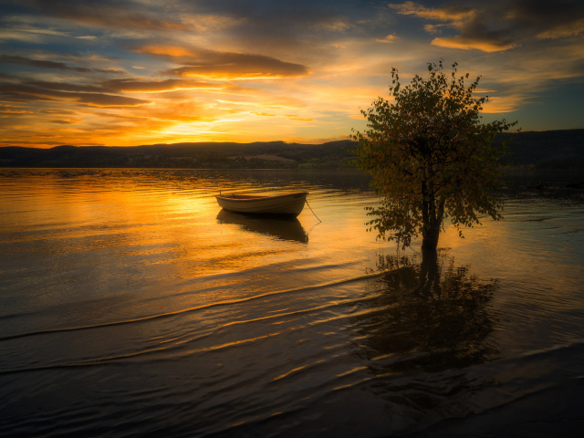 Лодка в воде спокойного озера на закате солнца