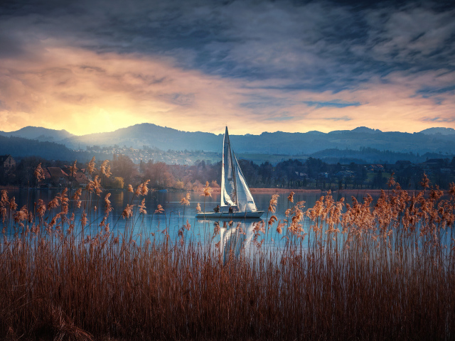 Парусная лодка на озере на закате солнца