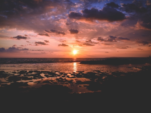 Закат яркого летнего солнца в небе над морем