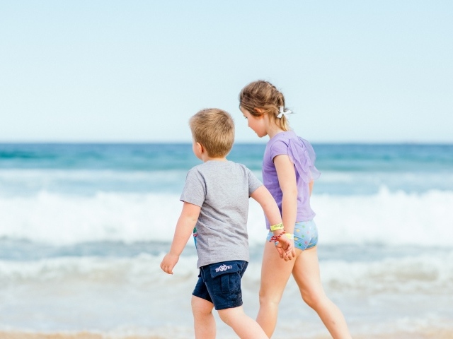 Мальчик и девочка идут по песку у моря