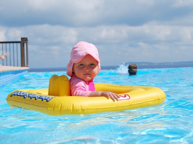 Ребенок со спасательным кругом плавает в бассейне