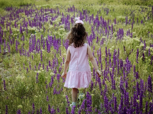 Девочка в розовом платье гуляет по полю с цветами