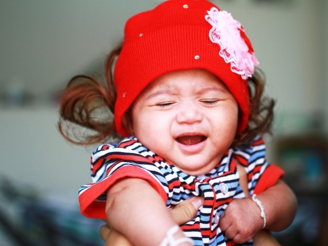 Девочка в красной шапке плачет на руках