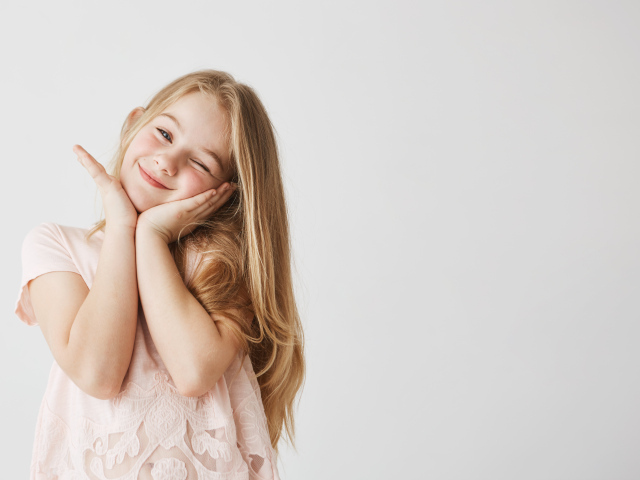 Красивая маленькая длинноволосая девочка на сером фоне