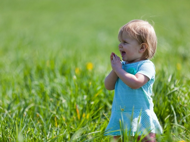 Веселая девочка на поле с зеленой травой