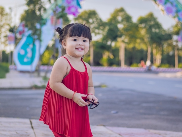 Веселая маленькая девочка азиатка в красном платье