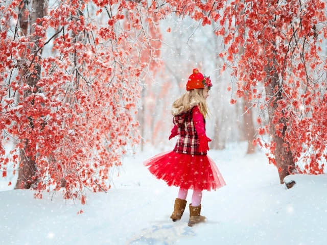Милая девочка в заснеженном лесу с деревьями с красными листьями