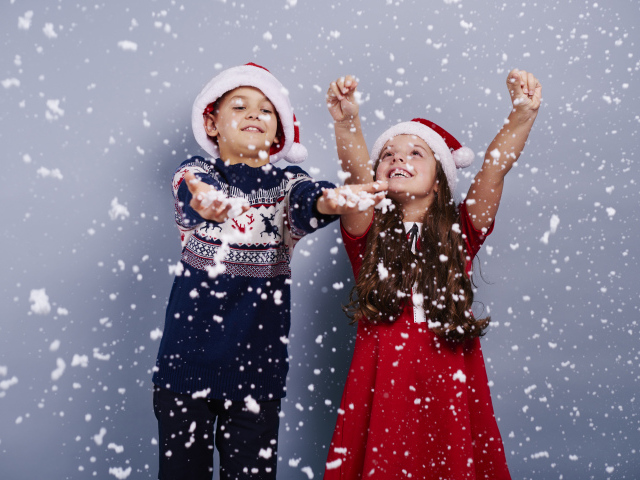 Маленькие мальчик и девочка ловят снег