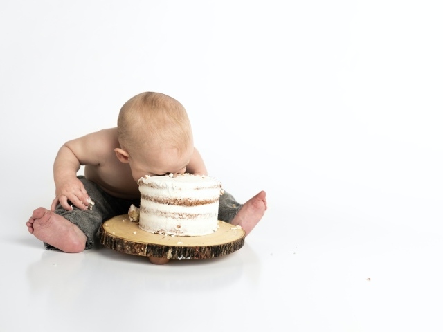 Маленький мальчик ест праздничный торт на белом фоне